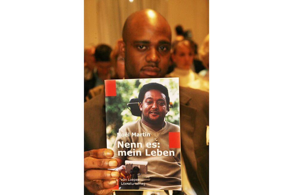 Negus Martin with his father's book “Nenn es: mein Leben” (Call it: my life). The Briton was the victim of a xenophobic attack in the German community of Mahlow (Teltow-Fläming) in 1996. The 47-year-old Noel Martin, who lives in Birmingham, England, has been paraplegic ever since. Through a fund he promotes youth exchange and is active against racism.