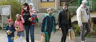 A family walking home with pre-packed food distributed at the window of the Salvation Army in the Paunsdorf district of Leipzig. Donations of food and, as needed, homemade face masks are distributed by municipal companies and by the Bundesliga club RB Leipzig. Photo taken on 15.04.2020. 