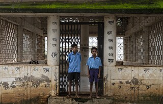 Two school kids stand at the entrance of the meeting hall that was once used to host conferences amongst the elders of the clan. The advent of modernity has led a wave of change through the village.