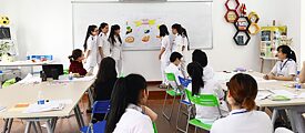 A group of students gives a presentation on the blackboard in a classroom. They are all wearing nurses' clothes.