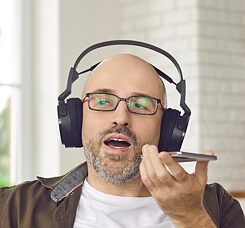 Mann mit Kopfhörern spricht in ein Handy