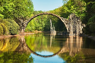 <b>Rakotzbrücke: Devil’s bridge with the perfect reflection</b><br/>Anyone keen on photo safaris should definitely head for the Rakotzbrücke at Kromlau in Saxony. Built in 1882 in a landscaped park that is Germany's largest rhododendron garden, the "devil's bridge" forms a perfect circle with its reflection in the waters of the lake below. The extraordinary sight is made all the more magical by the basalt rocks thrusting out of the water. 