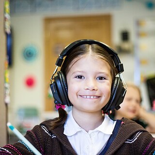 Ein Mädchen mit Kopfhörern in einem Klassenzimmer