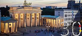 Brandenburger Tor illuminated at dusk, next to it is the logo of the Europanetzwerk Deutsch for the 30th anniversary