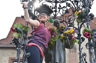 A freshly graduated PhD student climbs up the Gänseliesel fountain to give her flowers.
