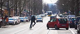 Cyklista se v silničním provozu vyhýbá parkujícímu autu.