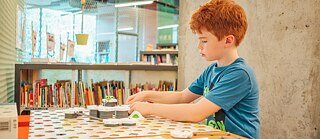 Foto de un niño sentado jugando un juego de mesa en la biblioteca