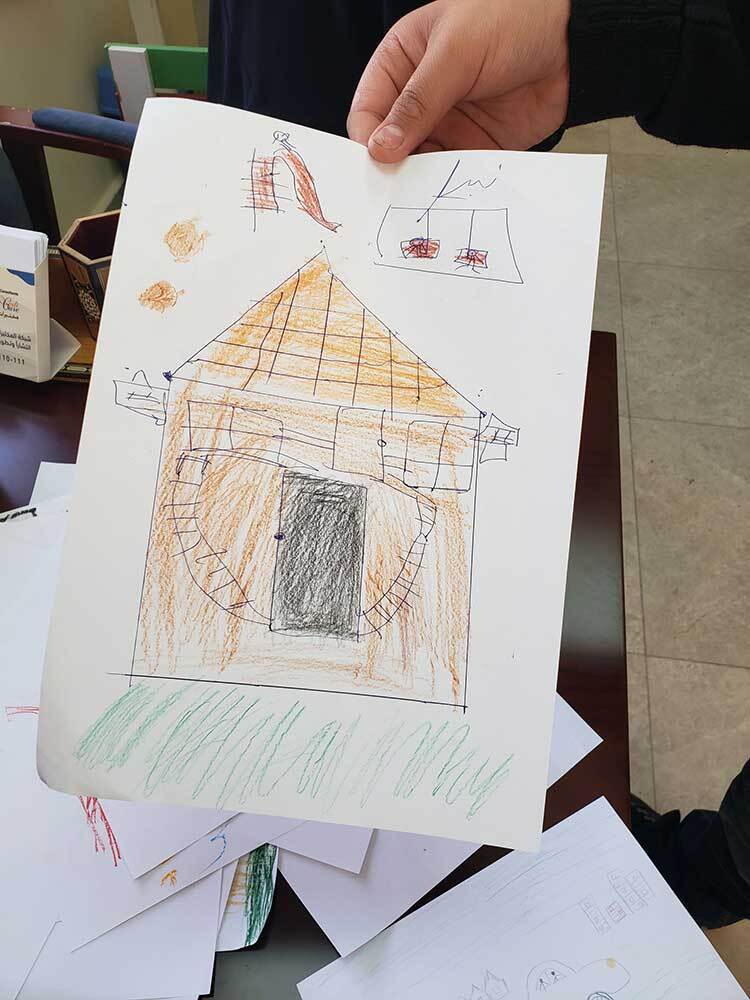 L'enfant Salam montre une image qu'il a dessinée lors d'une séance avec la psychologue et conseillère Hanan Walid.