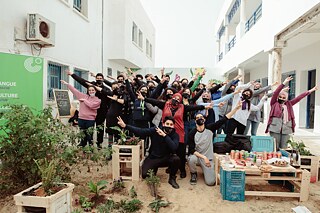Gruppenbild mit fröhlichen Jugendlichen im Schulhof vor Graffiti-Wand