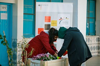 Jugendliche bepflanzen einen Blumentopf, der aus Paletten besteht.