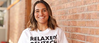 Junge Studentin trägt T-Shirt mit Relaxen Deutsch Lernen als Text und lächelt
