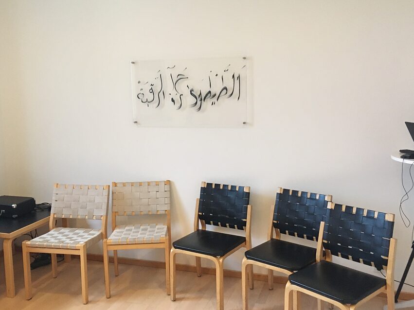 A circle of empty chairs in front of the calligraphy