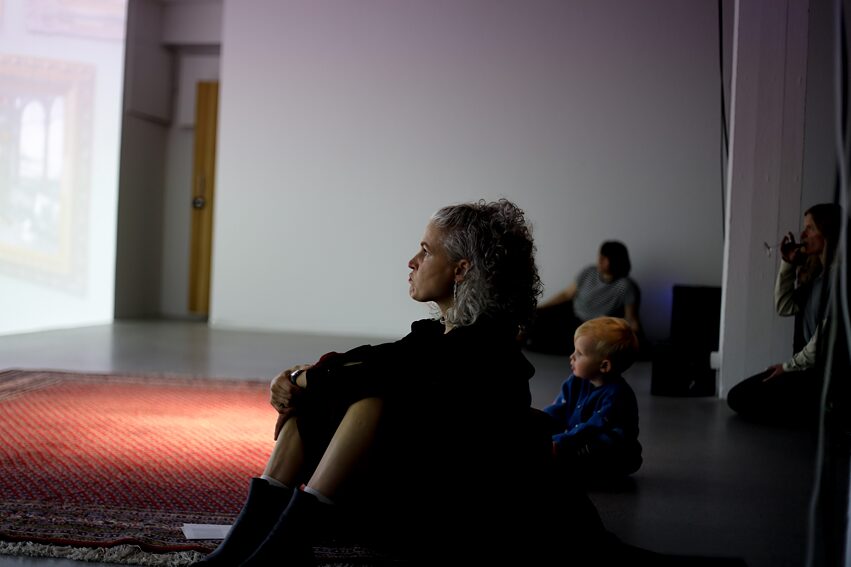 Woman sitting on the floor in front of the screen of ARK1 by Colette Sadler