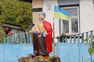 Скульптура вусатого козака з прапором України перед будинком