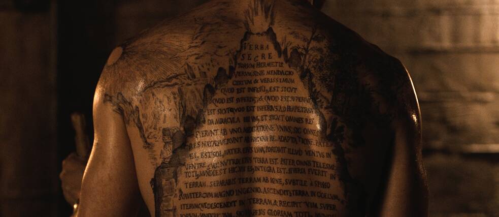 Ein Tattoo mit einer lateinischen Inschrift auf dem Rücken eines Mannes 