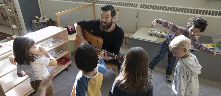 A teacher plays the guitar for his students
