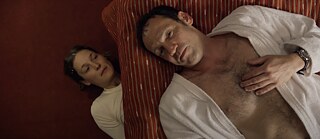 Szene aus dem Film 'Das Zimmermädchen Lynn'. Ein Mädchen liegt versteckt unter einem Bett und beobachtet einen Mann