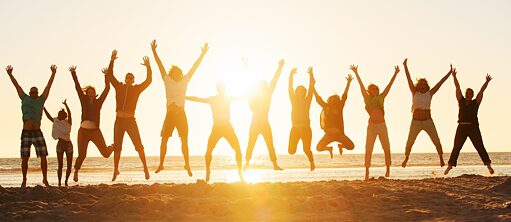 Menschen am Strand springen mit ihren Händen in der Luft