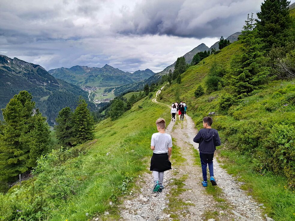 Jugendliche wandern einen alpinen Pfand entlang.