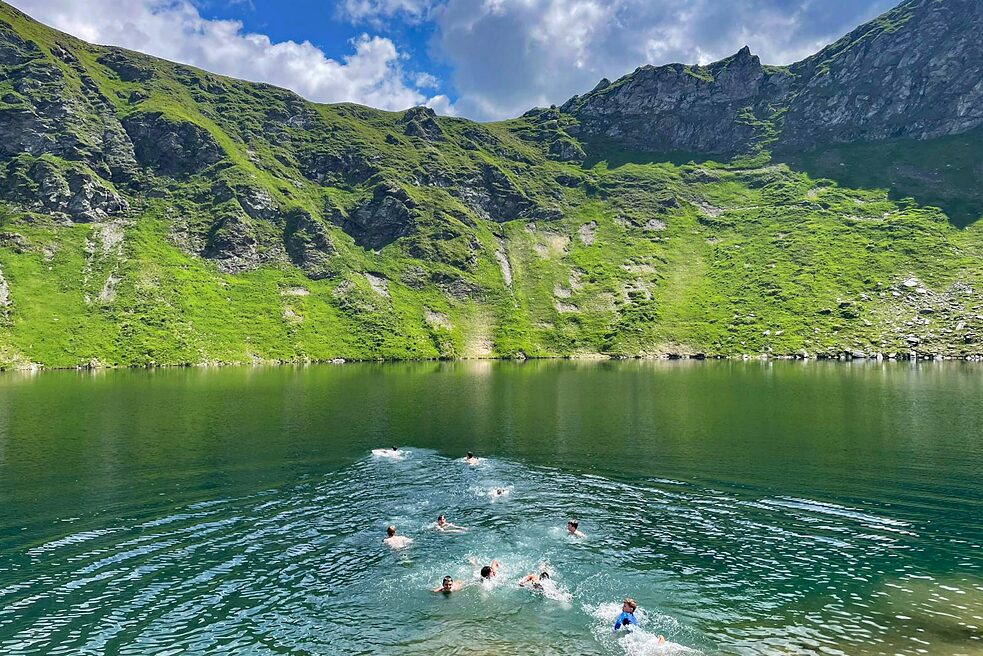 Jugendliche schwimmen in einem Bergsee.