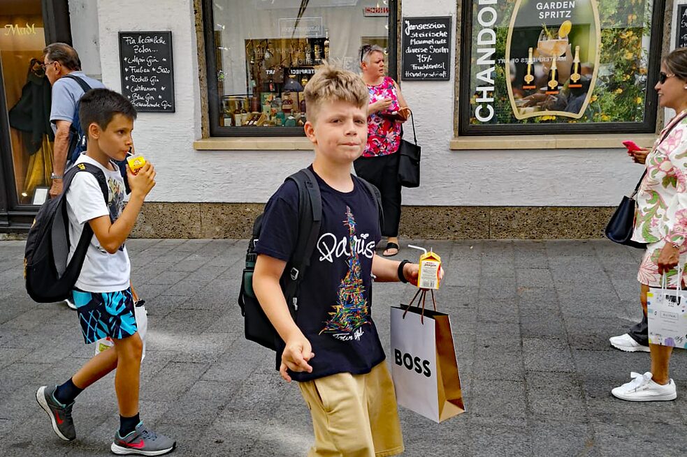 Kinder flanieren durch die Fußgängerzone von Salzburg mit Einkaufstaschen in der Hand.