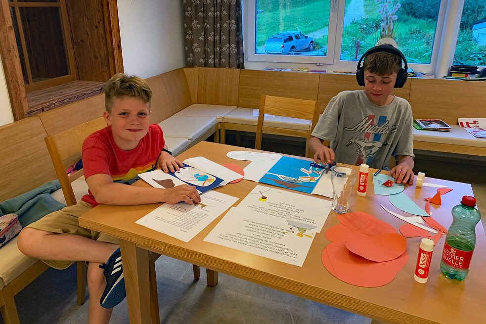 Jugendliche an einem Tisch basteln und malen.