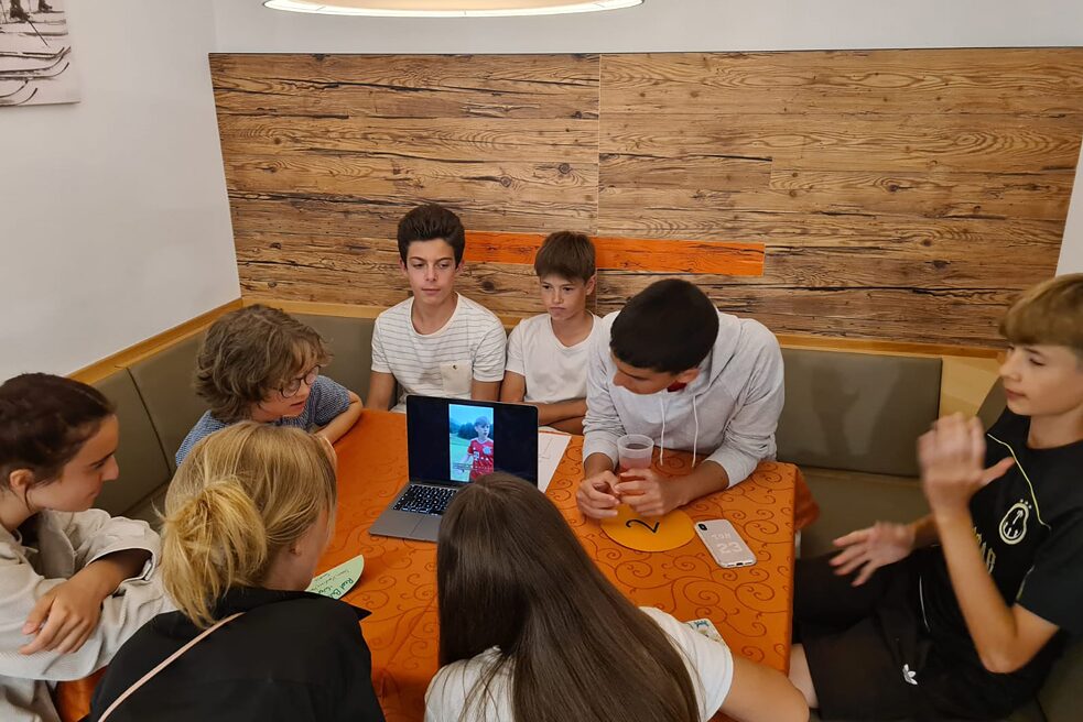 Jugendliche sitzen an einem Tisch und betrachten ein Video.