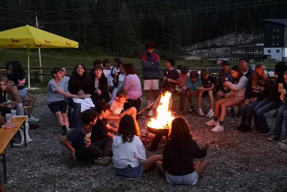 Jugendliche sitzen rund um ein Lagerfeuer.