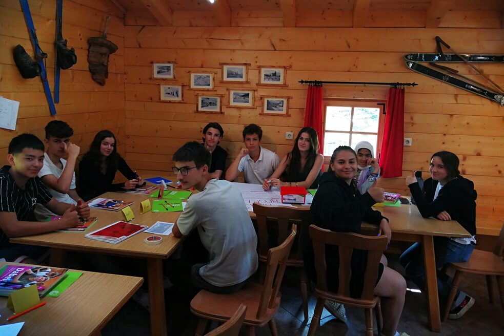 Jugendliche in einer Skihütte sitzen um einen Tisch und lernen.