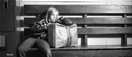 Das Mädchen Alice sitzt allein auf einer Bank. Schwarz-weiß Foto