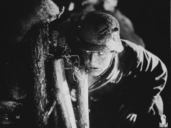 Filmstill aus „Westfront 1918”, das einen Soldaten hinter einer Palisade zeigt