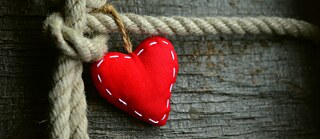 Ein Herz aus rotem Filz hängt an einer Kordel.