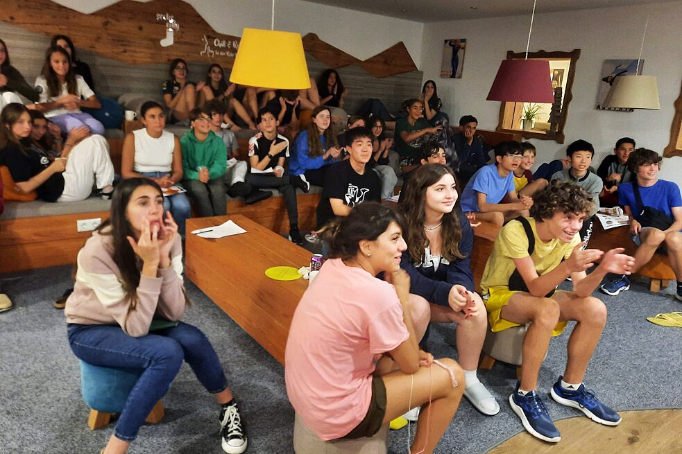 Eine Gruppe Jugendlicher versammelt in einem Raum blickt gespannt in eine Richtung.