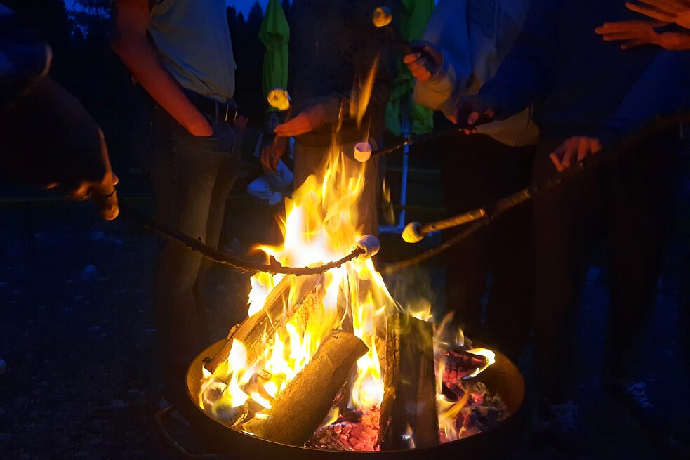 Jugendliche grillen Marschmellows auf einem offenen Lagerfeuer.
