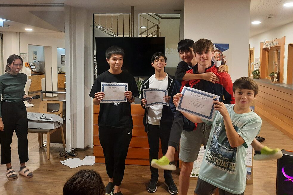 Eine kleine Gruppe Jugendlicher hält stolz Zertifikate in die Kamera.