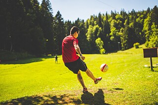 Ein Mann kickt einen Ball Richtung eines leeren Feldes