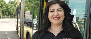 Smiling woman in front of a bus
