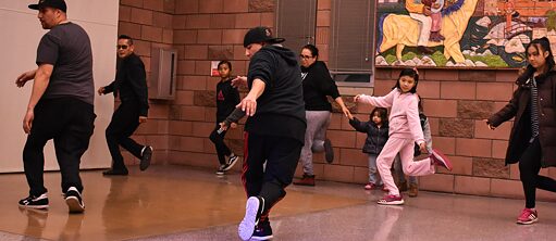 Acht Kinder und Erwachsene üben Hip-Hop zusammen in einen Kreis