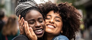 Two African ladies hugging each other in the streets of Germany. 