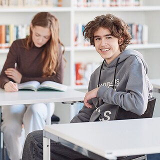 Ein junger Mann sitzt am Tisch in einer Bibliothek