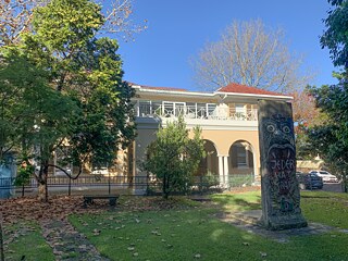 The outside of a heritate listed building with a piece of the Berlin wall in front of it