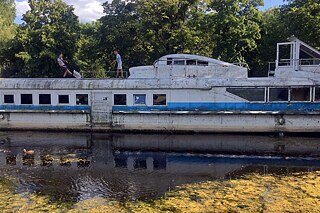 Луцьк, Волинська область, липень 2023 року: Двоє хлопчиків грають у футбол картонною коробкою на залишках затонулого корабля в міському парку Луцька.