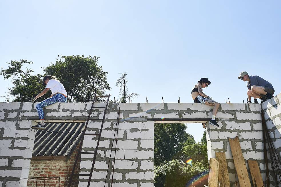 Команда з дівчат-волонтерів працює над щойно зведеними стінами хати пані Ніни у Лукашівці.