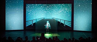 An image of an anime AI installation with audience in front  © Camille Blake Hatsune Miko