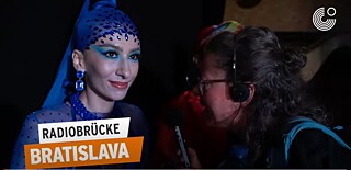 Radio Brücke Bratislava 2023 - Mitglied der queeren Community beim Ball of Shame mit blauer Kopfbedeckung