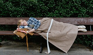 Eine Obdachlose schläft auf einer Parkbank.