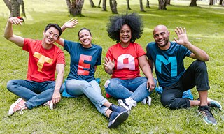 Vier Personen mit Buchstaben auf ihren T-Shirts, die das Wort Team bilden. 