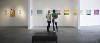 Dos visitantes de una galería observando las obras de arte. Vista posterior. Arte, Exposición