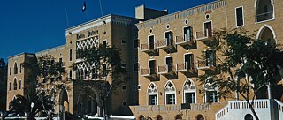 Facade of the imposing Ledra Palace Hotel in Nicosia. It is built of sandstone and has arched doors and small balconies.