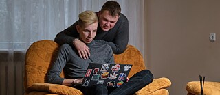 Photo is showing a male couple looking together at a laptop screen. 